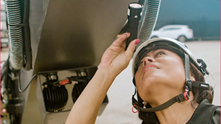 Kvinnlig ingenjör med hjälm som tittar upp och håller en ficklampa vid en besiktning
